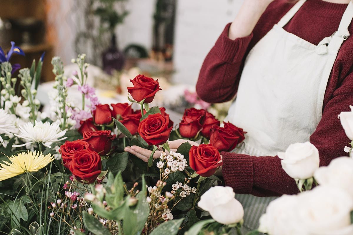 Un fleuriste devant un bouquet de roses rouges